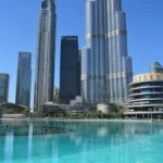 Calm Burj Lake and Dubai Mall exterior beside Burj Khalifa while Dubai Fountain suspended during mourning.