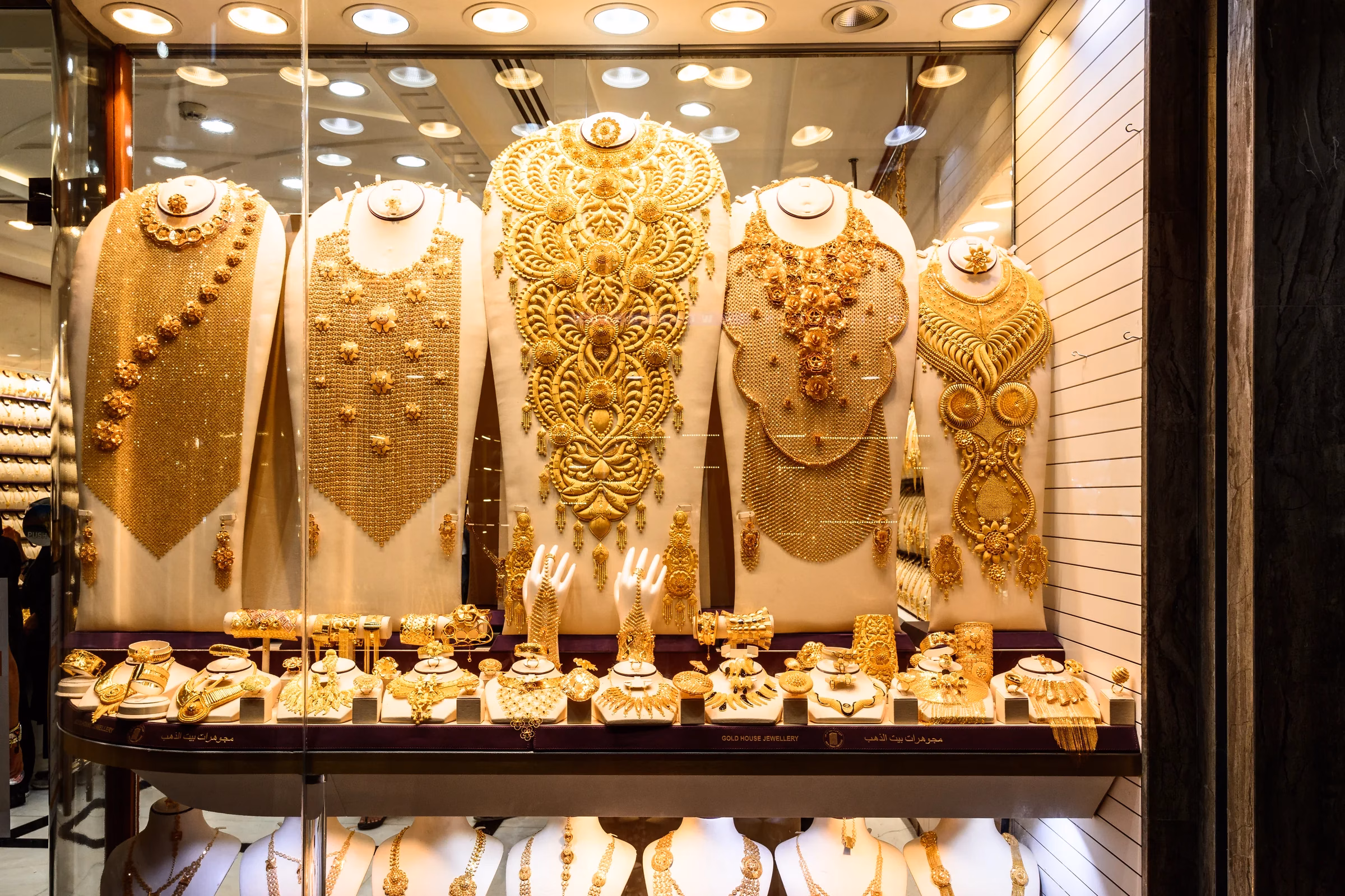 Ornate bridal gold necklaces displayed on mannequin busts in a Gold Souk shop window, the kind of heavy piece where making charges matter when buying gold in Dubai