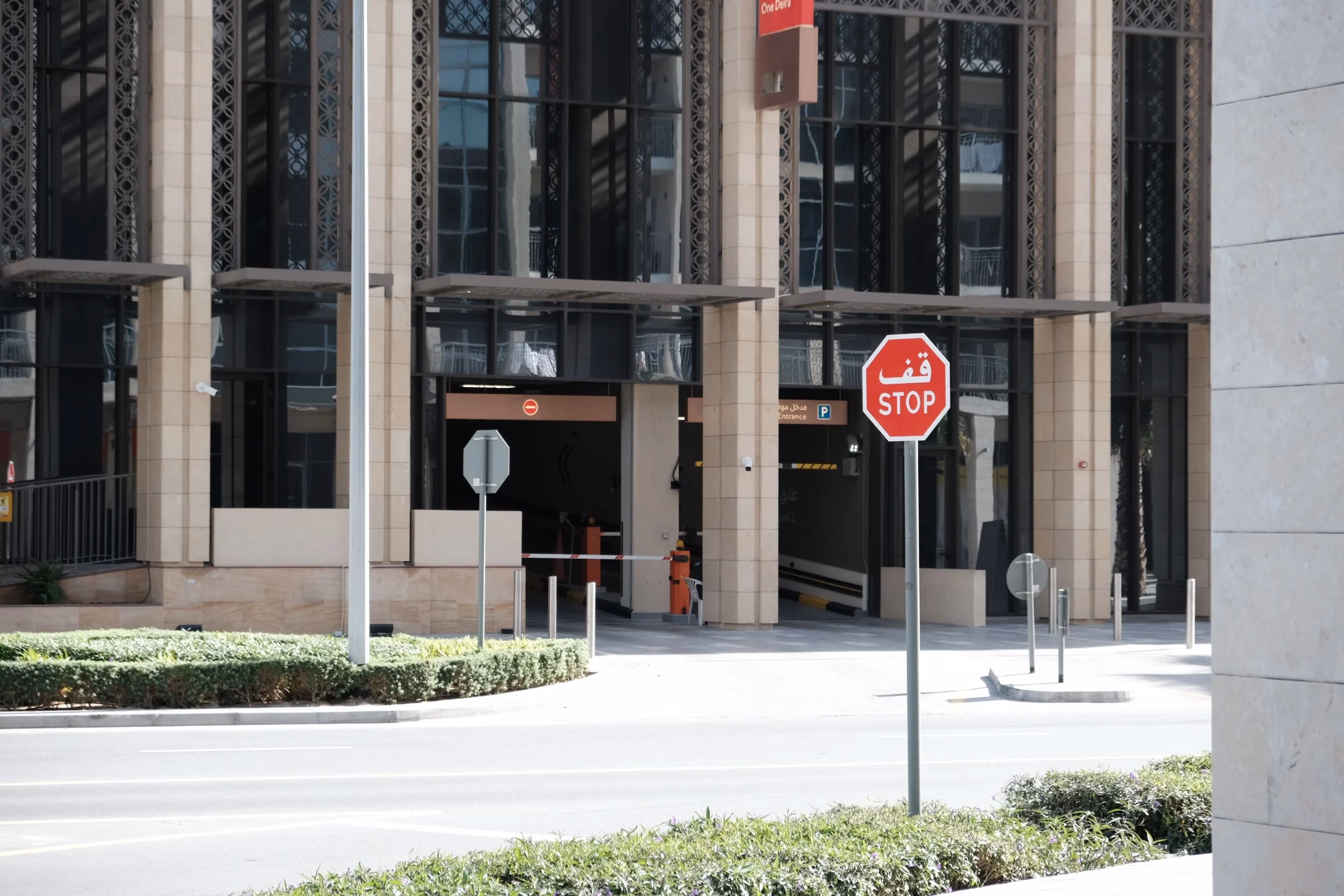 Bilingual Arabic and English stop sign outside a modern building in Dubai, where street signage is being redesigned
