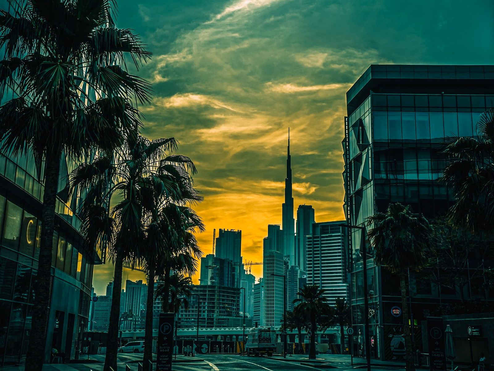 Palm-lined street in Dubai Design District (d3) with the Downtown Dubai skyline and Burj Khalifa in the distance