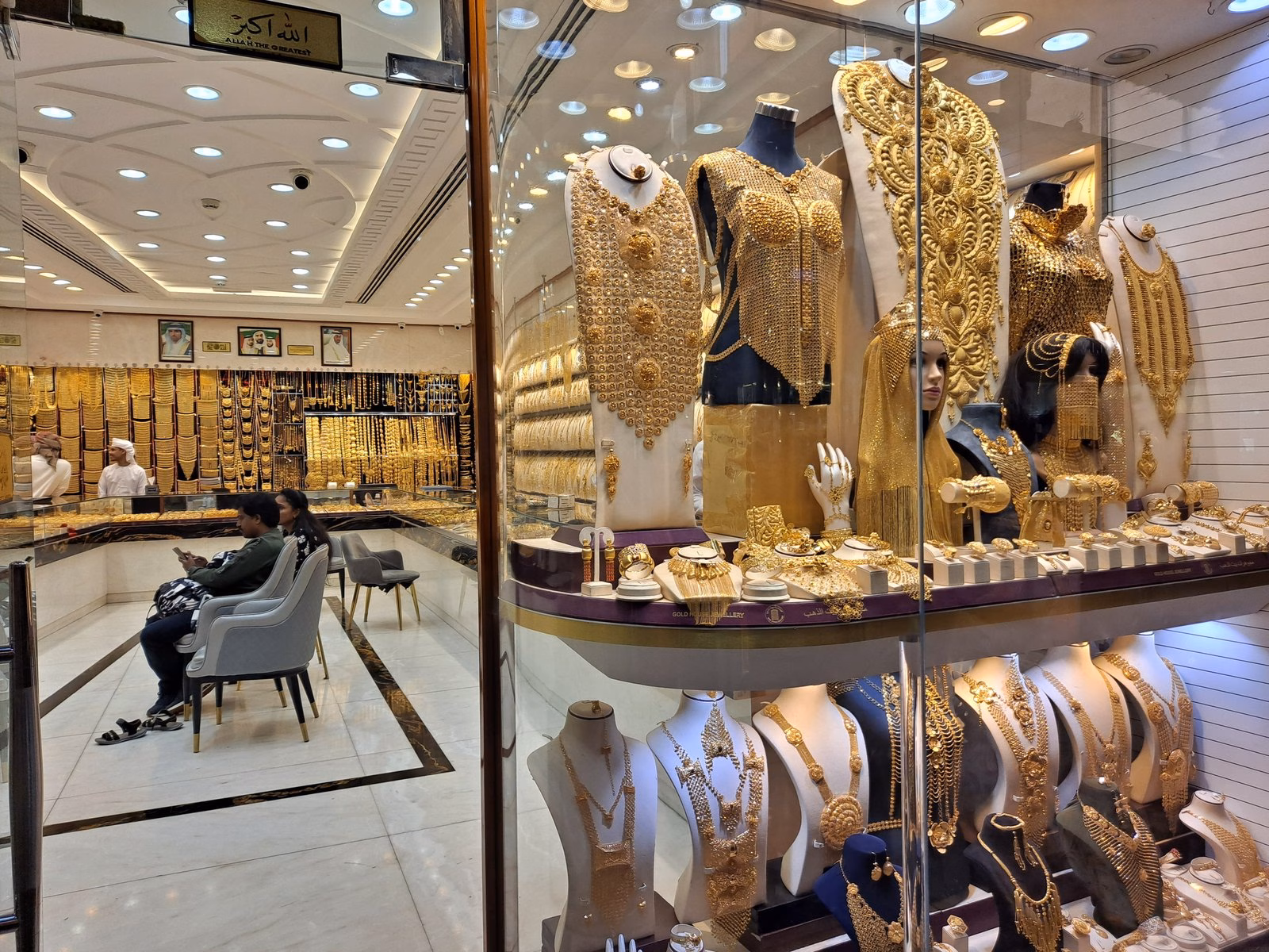 A brightly lit Dubai Gold Souk shop window filled with gold necklaces and bridal jewellery sets