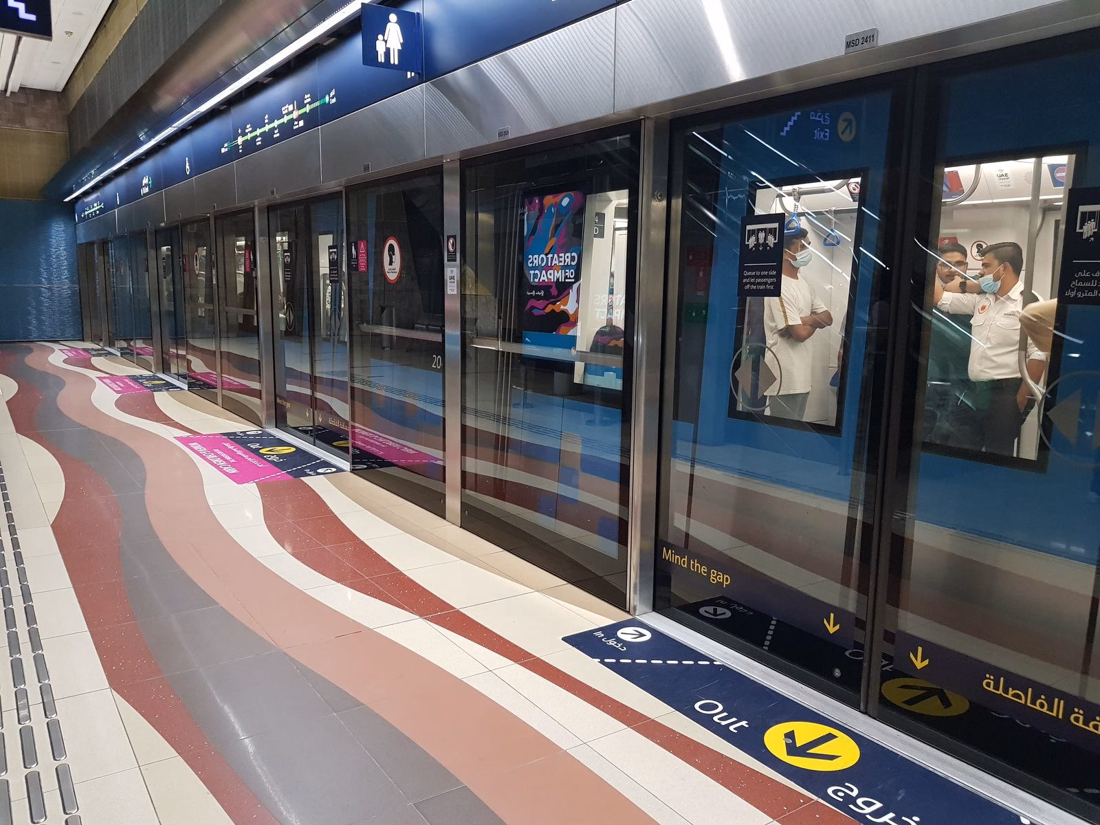 Platform screen doors and floor markings beside a Dubai Metro train, where People of Determination travel free with a blue nol card