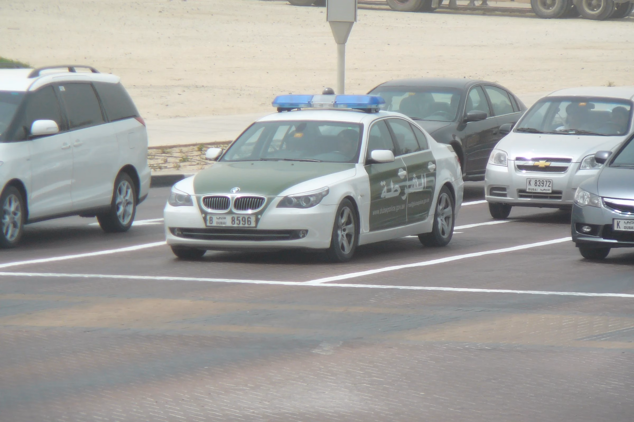 White and green Dubai Police patrol car parked in a car park, illustrating the police role in Dubai online reviews and social media crime cases
