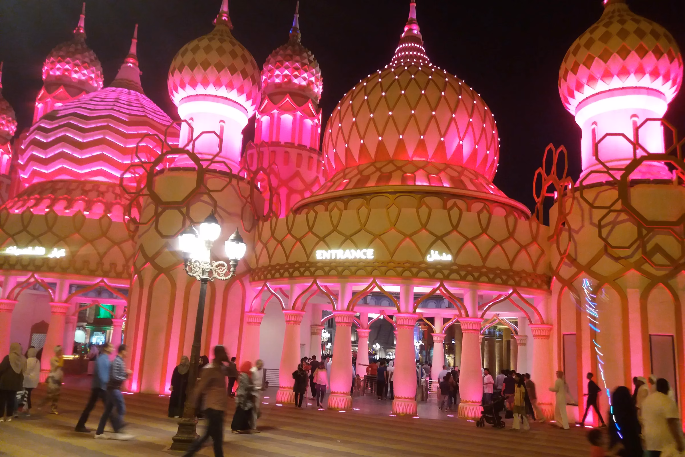 Pink-lit domes above an entrance at Global Village Dubai at night, where guests arrive for Season 31