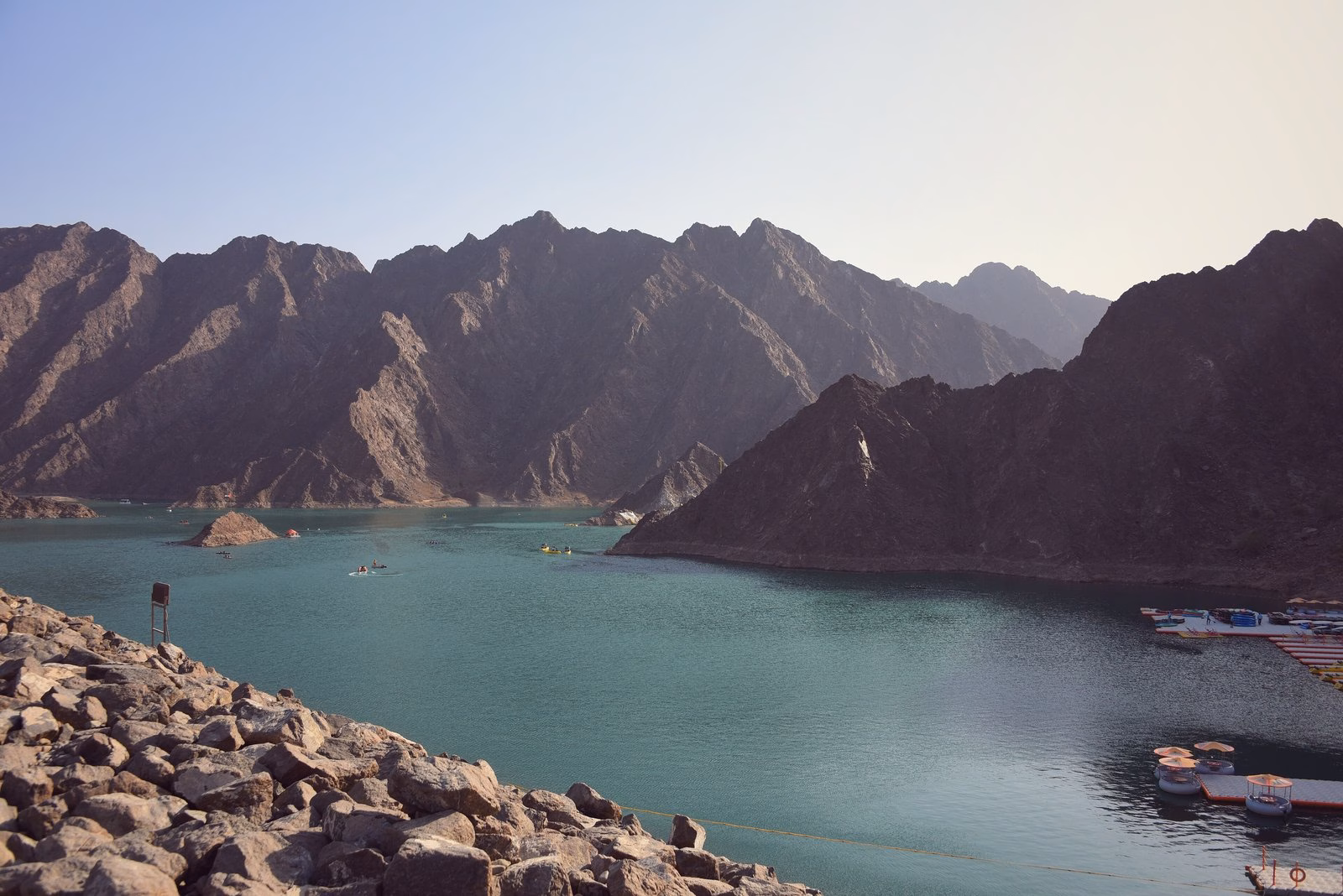 Turquoise water of Hatta Dam framed by the rocky Hajar Mountains in Hatta, Dubai, close to the Hatta camping grounds