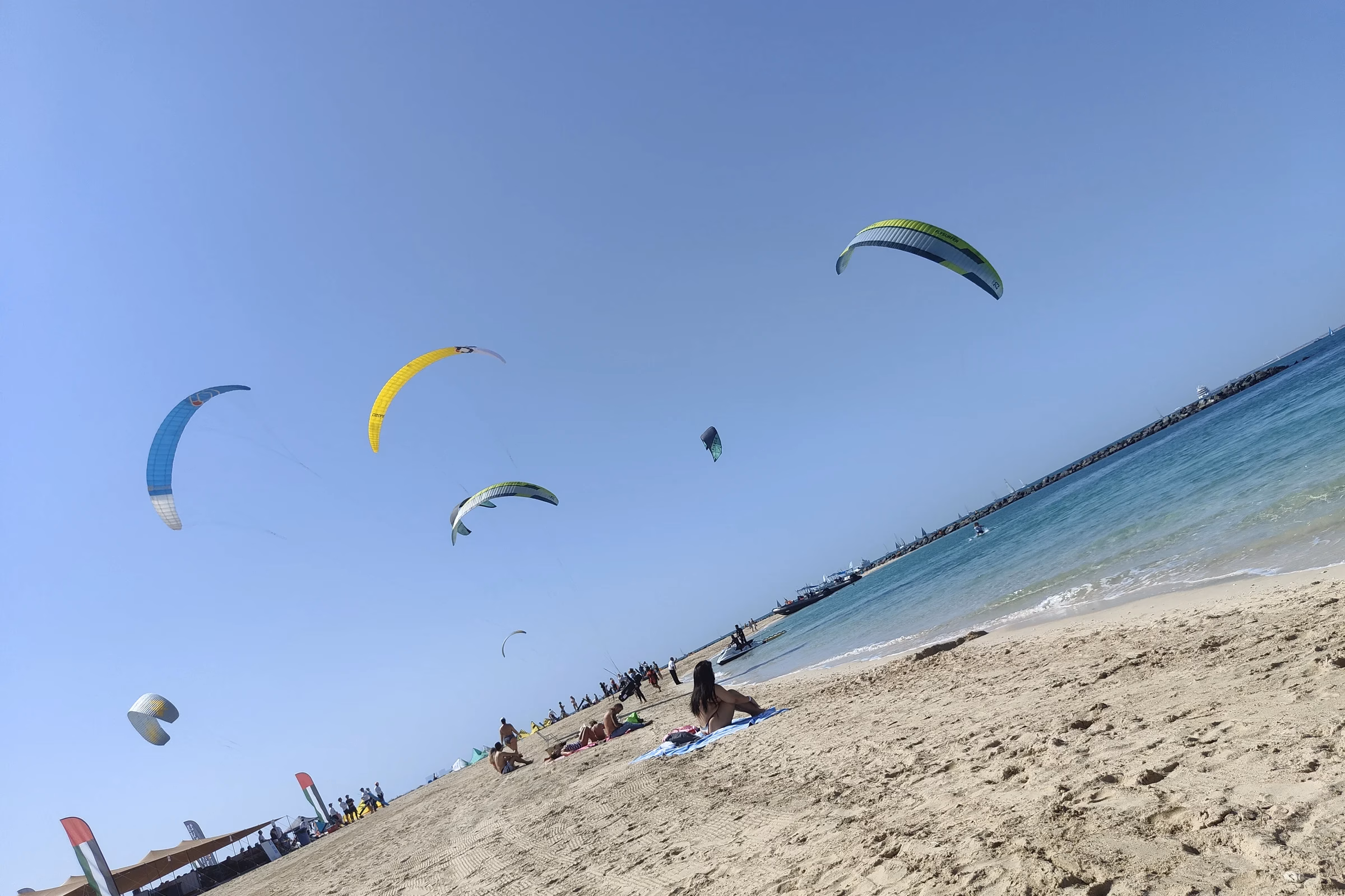 Colourful kites flying above the sand at Kite N Surf beach in Jumeirah, a launch area for kitesurfing in Dubai