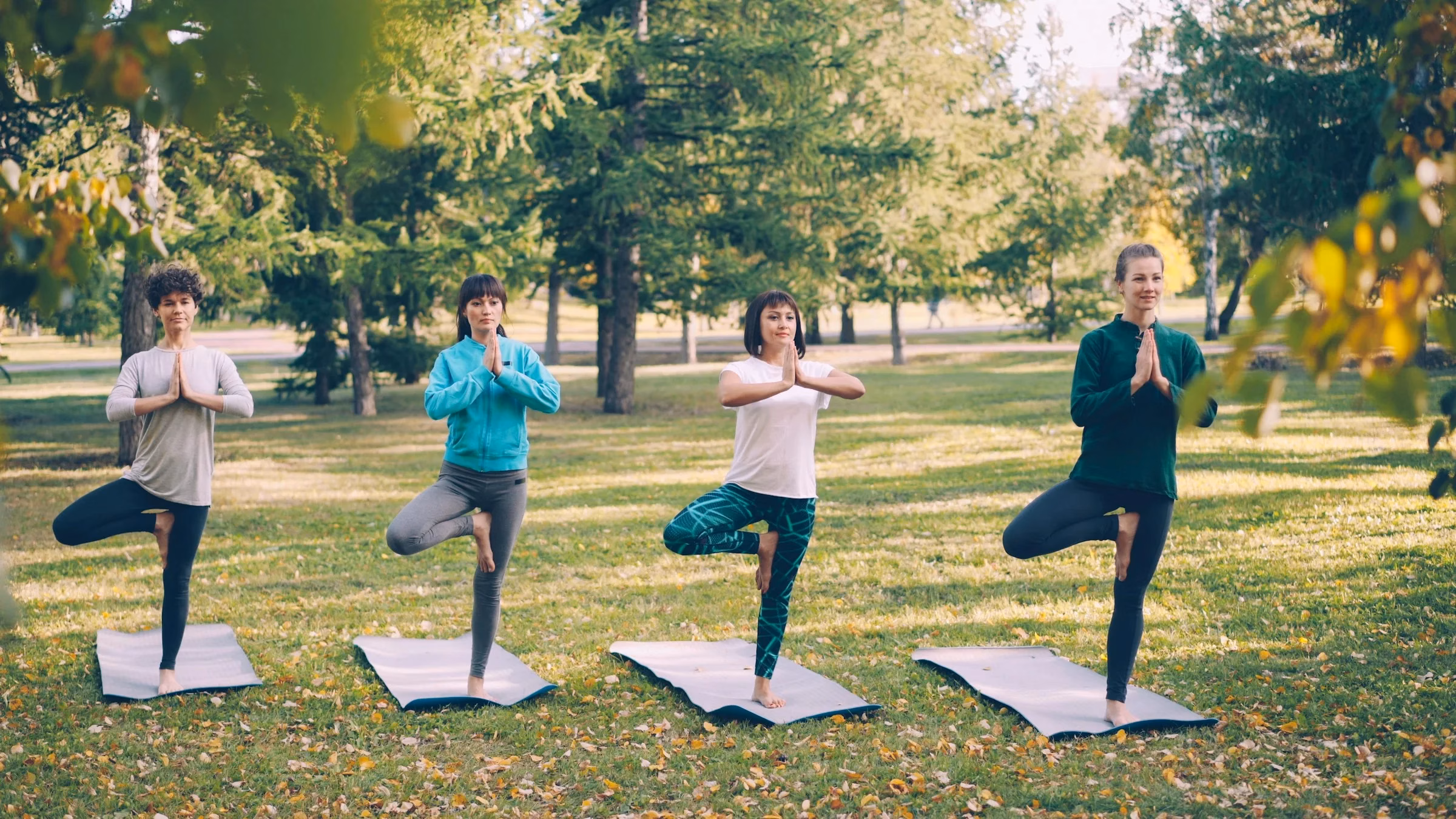 Group yoga class on mats in a leafy park, like the free wellness sessions at the Ripe Market Dubai