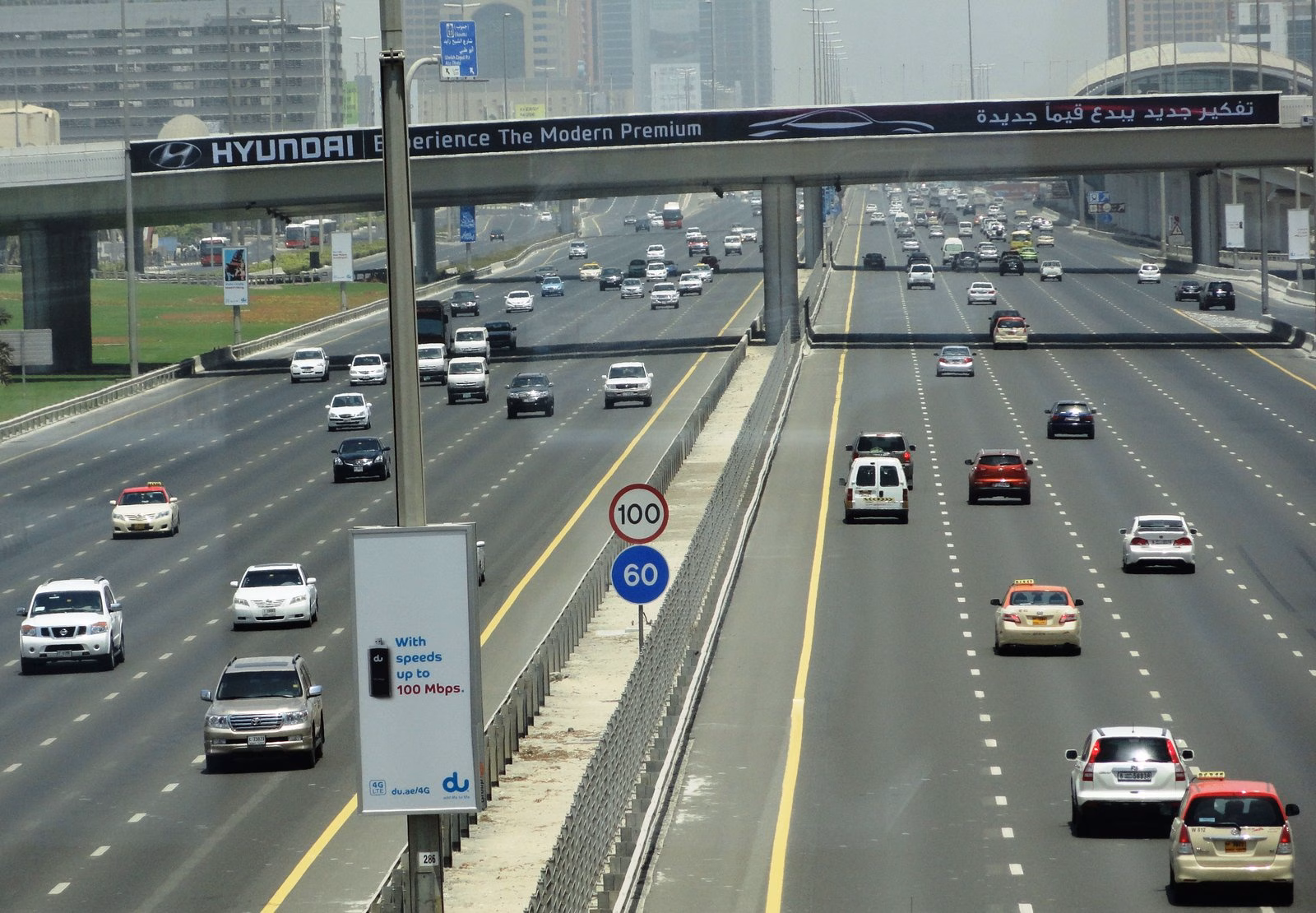 Traffic on Sheikh Zayed Road in Dubai with a 60 km/h speed sign and an overhead bridge, the corridor linked to the new World Trade Centre bridges