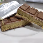 A Dubai chocolate bar broken open on a plate to show its green pistachio and kunafa filling