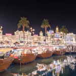 Floating market boats and illuminated pavilions reflected in the lake at Global Village Dubai at night, the scene awaiting guests on Global Village opening night